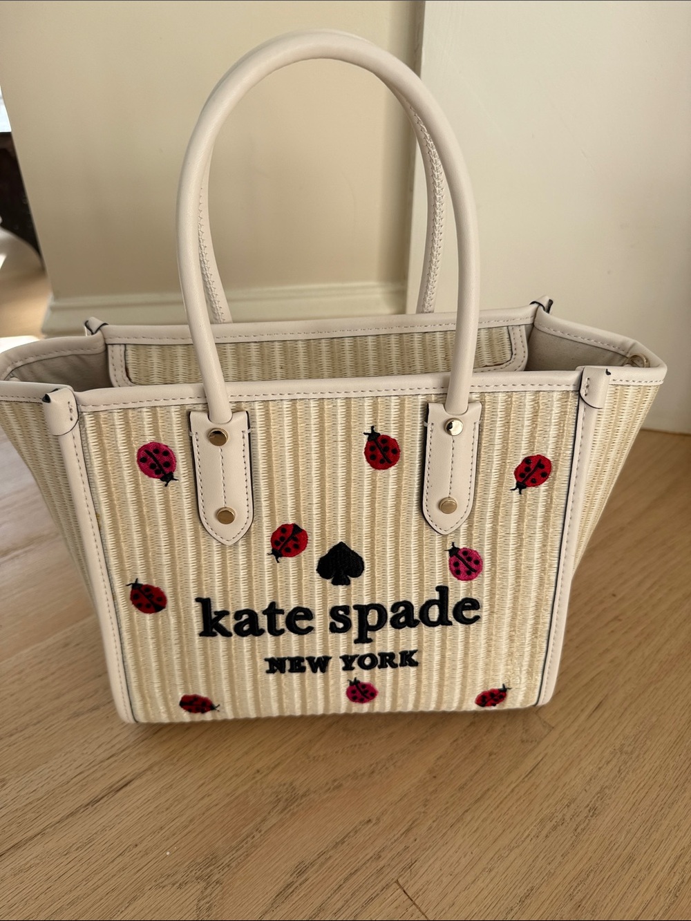 kate spade cream straw tote with red ladybug motifs